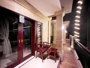 einen Balkon mit 2 Stühlen und einem Fenster in der Unterkunft Bali 85 Beach Inn in Padangbai