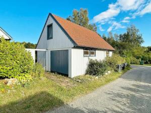 Biała stodoła z czerwonym dachem obok drogi w obiekcie Holiday home GÄRSNÄS w mieście Gärsnäs