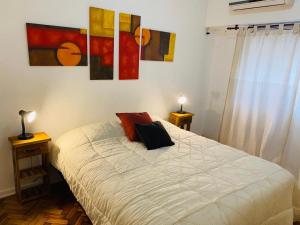 1 dormitorio con 1 cama y algunos cuadros en la pared en Departamento 3 ambientes con patio, terraza y parrila en Buenos Aires