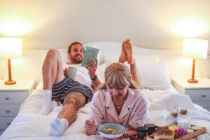 a man and a woman laying in bed with food at Harbourview House in Bermagui