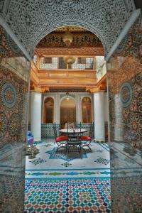 um quarto com uma mesa e cadeiras num piso de mosaico em Riad Fes Unique em Fez