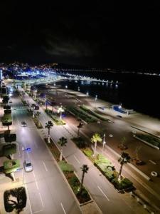 a city street at night with lights and palm trees at Nice Apartement au cornich de nador in Nador