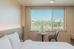 a bedroom with a bed and a chair and a window at Bloom Hotel in Seogwipo