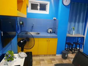 a blue and yellow kitchen with a sink and a fan at bluenest apartment in Manila