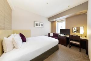 una camera d'albergo con un letto e una scrivania di KOKO HOTEL Kobe Sannomiya a Kobe