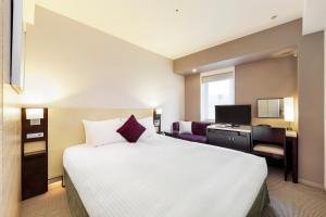 una camera d'albergo con un letto grande e una scrivania di KOKO HOTEL Kobe Sannomiya a Kobe