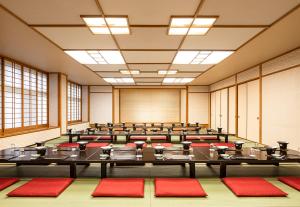 une salle de conférences vide avec des tables et des chaises rouges dans l'établissement The Gran Resort Kinosaki, à Toyooka