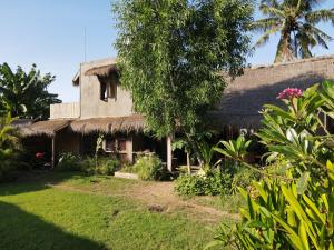 a house with a thatch roof and a yard at Flow Gili Air in Gili Air