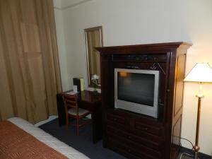 um quarto de hotel com uma televisão e uma secretária em L'Auberge de l'Aeroport Inn em Dorval