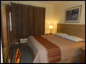 a hotel room with a bed and a chair at L'Auberge de l'Aeroport Inn in Dorval