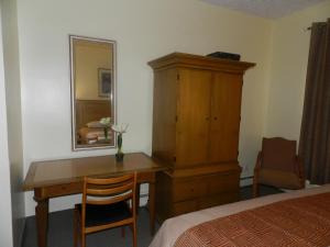 a bedroom with a desk and a dresser and a mirror at L'Auberge de l'Aeroport Inn in Dorval