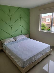 1 cama en un dormitorio con una pared verde en New 3 bedroom home in modern housing complex, en Manta