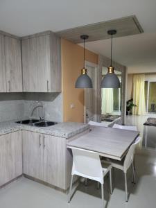 una cocina con armarios de madera y una mesa con sillas blancas. en New 3 bedroom home in modern housing complex, en Manta