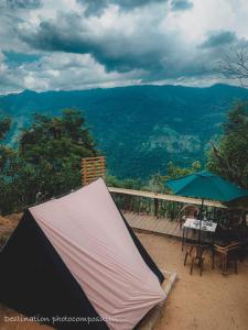 a tent and a table and umbrella on a deck at The Cliff Tea Glamping in Badulla