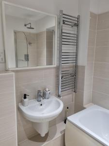 een badkamer met een wastafel, een toilet en een spiegel bij Chi's apartment in Barking