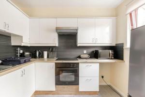 una cocina con armarios blancos y electrodomésticos de acero inoxidable en The Summit Apartment Aberdeen City Central Perfect Short or long stay en Aberdeen