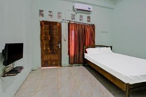 ein Schlafzimmer mit einem Bett, einem TV und einer Tür in der Unterkunft SPOT ON 91771 Homestay Bang Haji in Praya