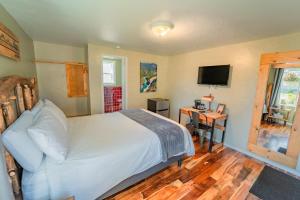 a bedroom with a bed and a desk with a television at Evergreen Motel in Libby