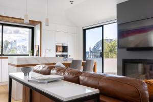 a living room with a leather couch and a fireplace at Barangaroo Park Apartments by Urban Rest in Sydney