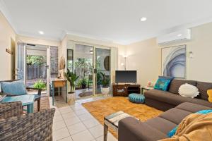un soggiorno con divano e TV di Treetops Lakeside Apartments a Byron Bay