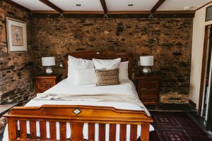 1 dormitorio con cama de madera con sábanas y almohadas blancas en Mintaro Cottage, en Mintaro