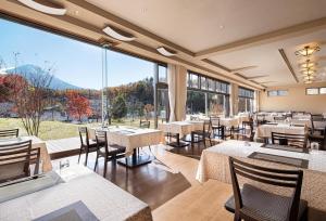 a restaurant with tables and chairs and a large window at The Gran Resort Princess Fujikawaguchiko in Fujikawaguchiko