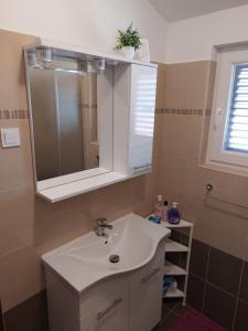 een badkamer met een witte wastafel en een spiegel bij Apartment Silvana - 100 m from beach in Božava