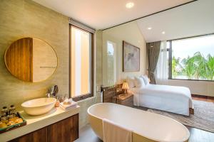 een badkamer met een bad, een bed en een wastafel bij Hoi An Memories Resort & Spa in Hội An