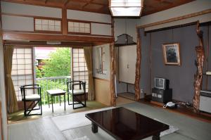 sala de estar con mesa y TV en Yoshidaya Ryokan, en Zao Onsen