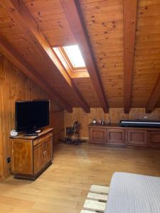 Habitación grande con TV y techos de madera. en Shanice’s House, en Pieve di Soligo