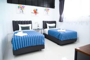 a bedroom with two beds with blue and white stripes at Baan Nern Khao Resort Pattaya in Ban Huai Yai