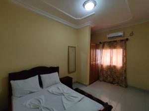 1 dormitorio con cama y ventana con cortina en DREAM'S HOUSE BONAMOUSSADI , STUDIO, en Douala