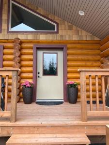 un porche de madera con una puerta blanca y dos plantas en Clear creek cabin, en Seward