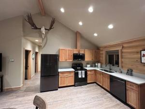 cocina grande con electrodomésticos negros y armarios de madera en Clear creek cabin, en Seward