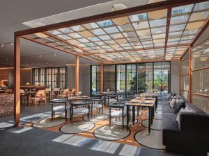 a restaurant with tables and chairs and windows at Hotel Indigo Hangzhou Uptown,Close to Westlake , boutique design hotel with freeflow minibar in Hangzhou