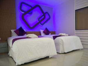 two beds in a room with a purple wall at Phitsanulok United in Phitsanulok
