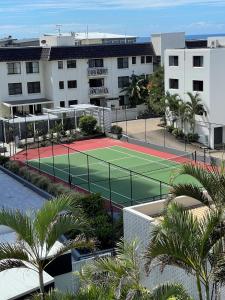 una pista de tenis frente a un edificio con palmeras en Catalina Resort, en Maroochydore