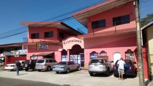 a pink building with cars parked in a parking lot at ECONOMIQUE in Jacó +3 photos