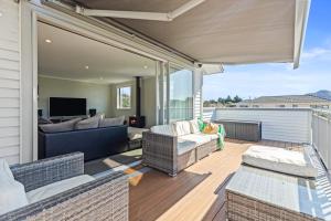 a patio with a couch and chairs on a deck at Campbell Road Classic - Mount Maunganui Bach in Mount Maunganui