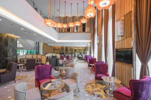 a restaurant with purple chairs and tables and a chandelier at Zenith Hotel Putrajaya in Putrajaya