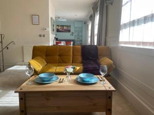 a living room with a yellow couch and a coffee table at Studio Flat Central Cheltenham Parking off road in Cheltenham