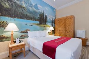 a hotel room with a bed and a painting of a mountain at European Hotel in Perth