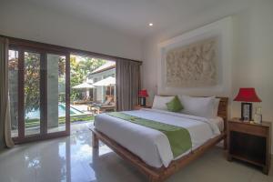 ein Schlafzimmer mit einem großen Bett und einer Glasschiebetür in der Unterkunft Villa Verano at Echo Beach Canggu in Canggu