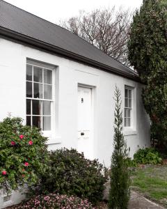 a white house with a white door and windows at Gaol House Cottages in Bicheno