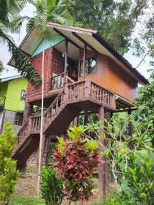 a wooden house with a balcony in the forest at Malulee KhaoSok Resort in Khao Sok