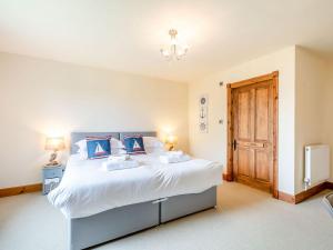 a bedroom with a large white bed with blue pillows at Seaviews And Hot Tub At Admirals Anchor in Portpatrick
