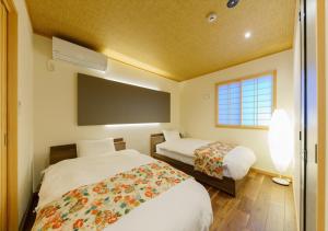 a bedroom with two beds and a flat screen tv at YADOYA 雀 in Tokyo
