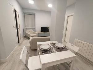 ein weißes Wohnzimmer mit einem Tisch und einem Sofa in der Unterkunft Cómodo apartamento en el centro de Bermeo. in Bermeo