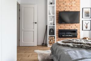 a bedroom with a brick wall with a tv above a fireplace at Apartament pod Wierchem in Zakopane