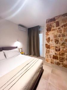 a bedroom with a bed and a stone wall at Olea Relais in Conversano